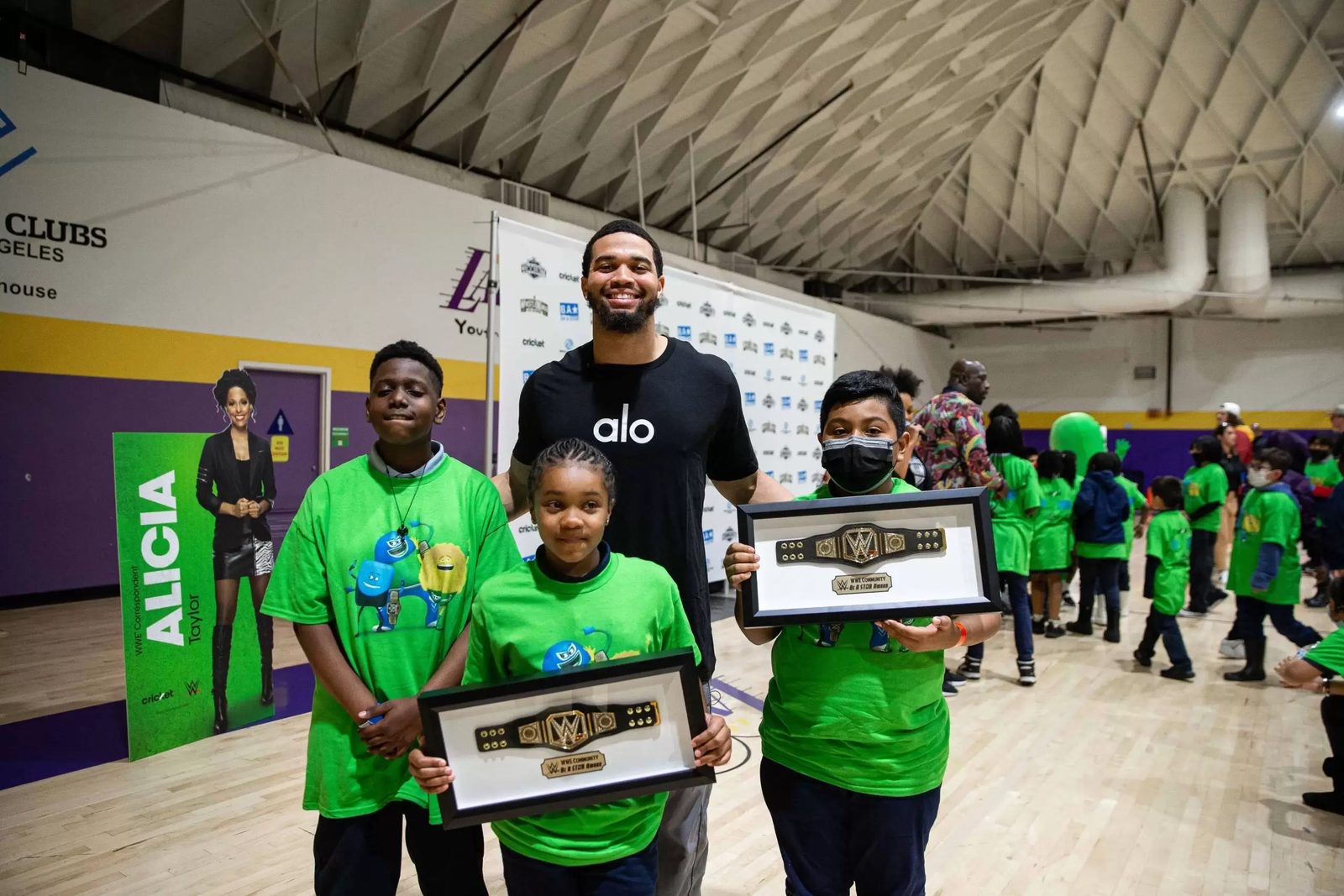Youth in green shirts holding framed championship belts